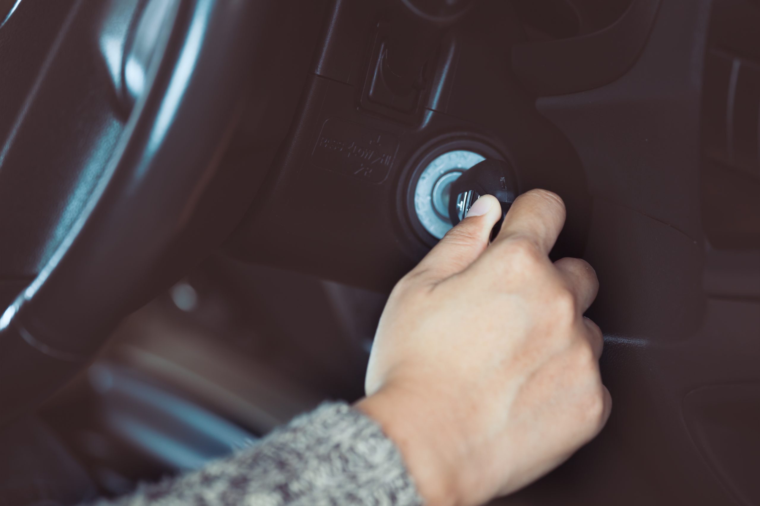 Woman hand put key into the ignition and starts the car engine